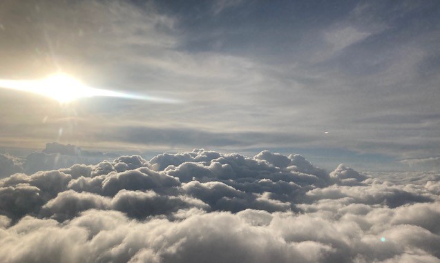 飛行機の窓から見える太陽と雲